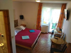 a small bedroom with a red bed and a window at Hotelik Komandor in Władysławowo