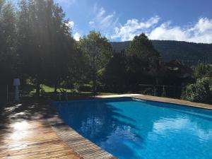 a blue swimming pool with a wooden walkway and trees at Le Petit Skieur B&B in Le Sappey-en-Chartreuse