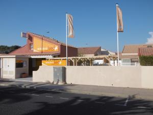 un edificio con dos banderas al lado de una calle en Holidayland Residence Plein Sud villa 60m2 6 couchages, en Narbonne-Plage