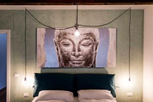 a painting of a face hanging above a bed at Stay COOPER l Goethe Suite in Bolzano