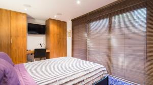 Schlafzimmer mit einem Bett, einem Schreibtisch und einem TV in der Unterkunft Romantic Bungalow in Notting Hill in London