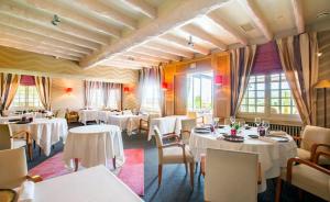 un restaurant avec des tables blanches, des chaises et des fenêtres dans l'établissement auberge le relais, à Reuilly-Sauvigny