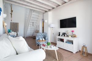 a living room with a white couch and a tv at Panorea Complex - Mykonos in Ano Mera