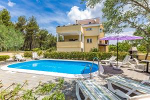 basen z krzesłami i parasolem oraz budynek w obiekcie Apartments Villa Orion w mieście Kožino