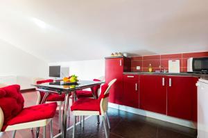 kuchnia z czerwonymi szafkami, stołem i krzesłami w obiekcie Apartments Villa Orion w mieście Kožino