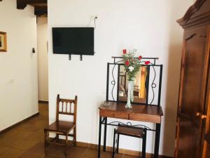 a room with a table with a vase of flowers and a television at Hotel Restaurante Calderon in Arcos de la Frontera