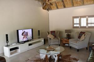 a living room with a tv and a table at Luvivane Luxury Villa in Marloth Park