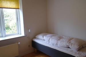 Cama en una esquina de habitación con ventana en Agervig Bed & Breakfast, en Næsbjerg