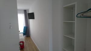 Habitación con pared blanca y estante para libros. en Pokoje gościnne Anis en Ustka