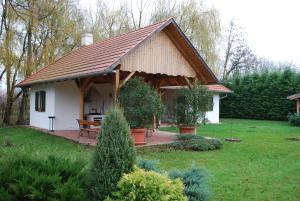 mały biały dom z drewnianym dachem w obiekcie Rozália Vendégház w mieście Sarród