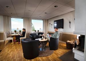 Långbergets Sporthotell في Sysslebäck: يجلس شخصان في غرفة بها موقد