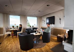 two people sitting in a room with a fireplace at Långbergets Sporthotell in Sysslebäck