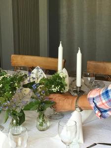 eine Person, die an einem Tisch mit Kerzen und Blumen sitzt in der Unterkunft Mellby 11 Bed & Breakfast in Kivik