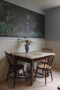 einen Holztisch mit zwei Stühlen und eine Vase mit Blumen in der Unterkunft Mellby 11 Bed & Breakfast in Kivik