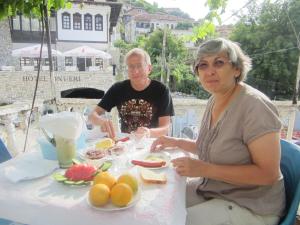 a man and a woman sitting at a table with food at Guest House Adi Doga in Berat