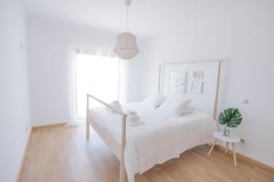 Dormitorio blanco con cama blanca y maceta en Casas de Mar - Sereia, en Olhão