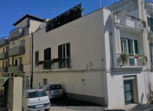 a white building with cars parked in front of it at Residenza del Maestro in Matera