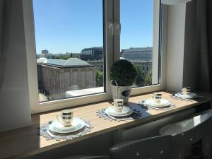una mesa con tazas y platillos delante de una ventana en Exclusive Apartments Smolna, en Varsovia