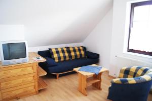 a living room with a couch and a tv at Szanyi Vendégház in Hegykő