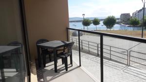 balcón con mesa y vistas al agua en Apartamentos Turísticos Playa de Osmo, en Corme - Puerto