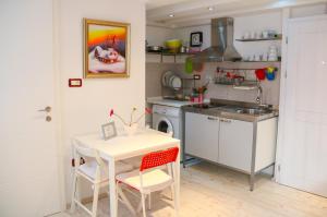 una pequeña cocina con mesa blanca y sillas en Apartman Luca, en Piran