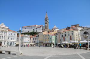 una plaza de la ciudad con una torre de reloj en el fondo en Apartman Luca en Piran