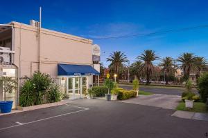 a parking lot in front of a building with palm trees at Alexander Motor Inn in Melbourne