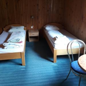 SrebrenicaにあるHM - konakのベッド2台、テーブル、椅子が備わる客室です。