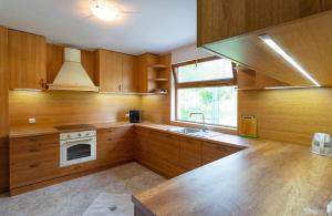 uma cozinha com armários de madeira, um lavatório e um fogão em Guest Houses Apriltsi em Kravenik