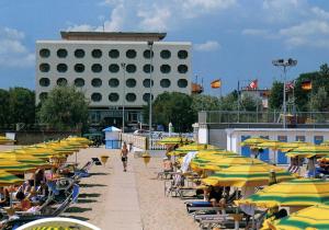 a beach with many chairs and umbrellas and a building at Hotel San Pietro in Cesenatico
