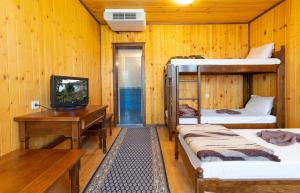 a room with two bunk beds and a desk and a television at Guest Houses Apriltsi in Kravenik