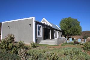 
a large white house with a blue roof at Matjiesvlei Cottages in Calitzdorp
