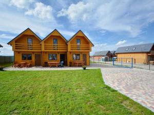 ein großes Holzhaus mit Rasen davor in der Unterkunft Domki u Jagody in Sarbinowo