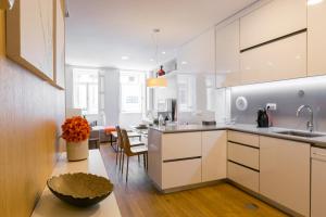 a kitchen with white cabinets and a dining room at Merc Porto Cedofeita Place in Porto