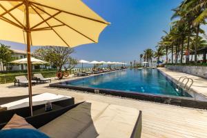 a large swimming pool with a yellow umbrella and chairs at Sunshine Apartment in 5* resort in Da Nang