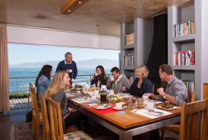 um grupo de pessoas sentadas em torno de uma mesa em um restaurante em Whalesong Lodge em Gansbaai