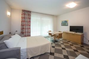 a hotel room with a bed and a desk and a television at Piazzi House in Sondrio