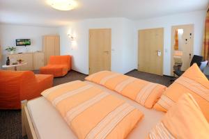 Zimmer mit 2 Betten und einem orangefarbenen Sofa in der Unterkunft Hotel Zum Birkenhof in Burow