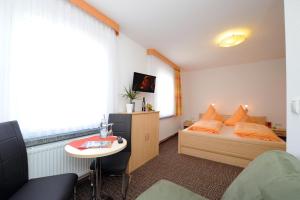 a small bedroom with a bed and a table at Hotel Zum Birkenhof in Burow