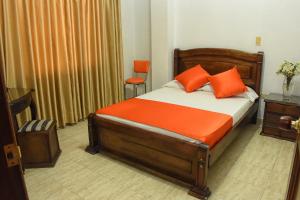 a bedroom with a bed with orange pillows at Hotel el Lago 2 in Pereira
