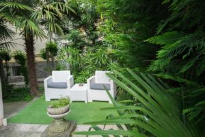 un jardín con sillas blancas y plantas verdes en B&B Pereuka, en Rovigo