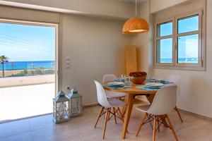 a dining room with a table and chairs and the ocean at Villa EcoBlu in Ayía Kiriakí