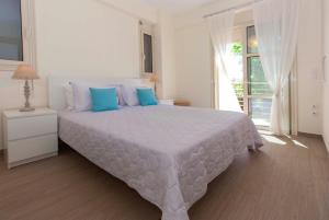 a white bedroom with a large bed with blue pillows at Villa EcoBlu in Ayía Kiriakí