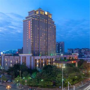 een hoog gebouw met lichten aan in een stad 's nachts bij Cinese Hotel Dongguan Shijie in Dongguan