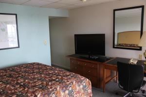 a bedroom with a bed and a desk with a television at Midlands Lodge in Hastings
