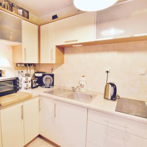 een keuken met witte kasten en een wastafel bij Apartament Sosnowa 13 in Mielno