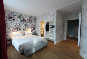 a bedroom with a large white bed with a floral wallpaper at MOMA1890 Boutique Hotel in Munich