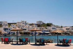 a group of chairs and tables with umbrellas on a beach at Elena Studios in Panormos