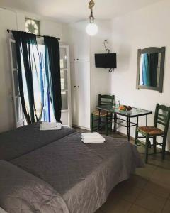 a bedroom with a bed and a table with chairs at Elena Studios in Panormos
