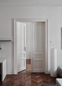 an open white door in a white room with wood floors at Apartment Trdinova in Ljubljana